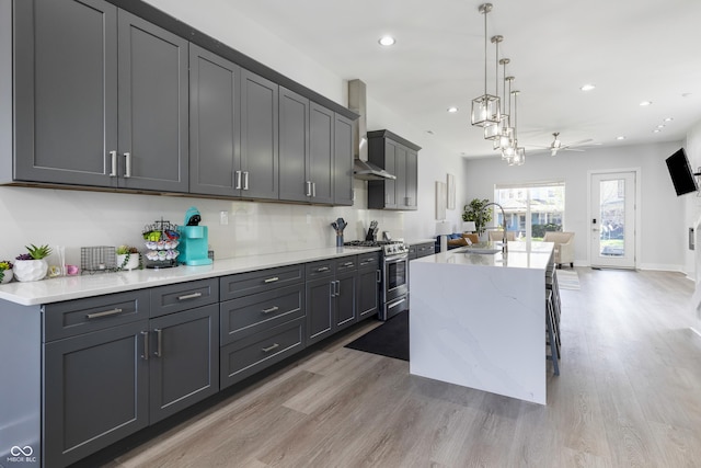 2226 Central Ave, Indianapolis, IN 46205 - kitchen featuring stainless steel gas range oven, wall chimney exhaust hood, light wood-type flooring, and a sink