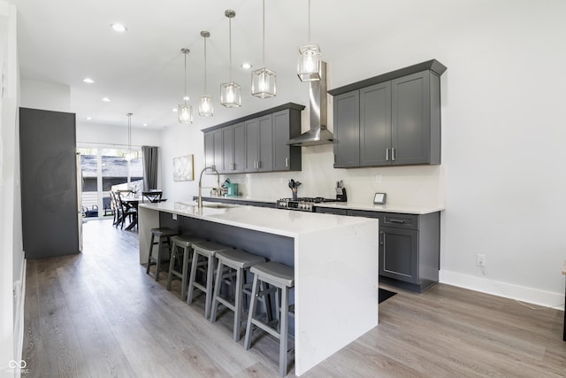 2226 Central Ave, Indianapolis, IN 46205 - kitchen featuring light wood-style flooring, a center island with sink, wall chimney range hood, and a sink