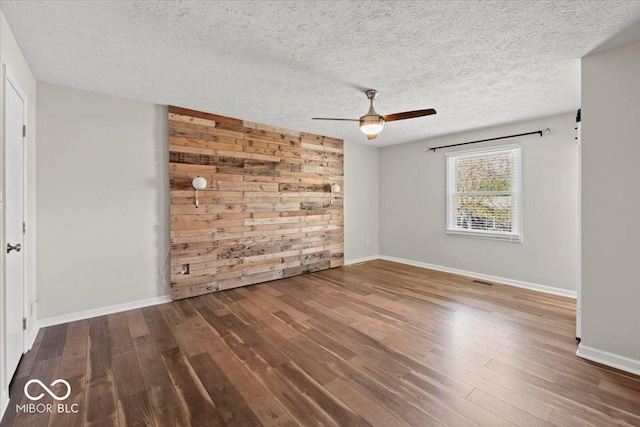 spare room with wooden walls, baseboards, ceiling fan, and wood-type flooring