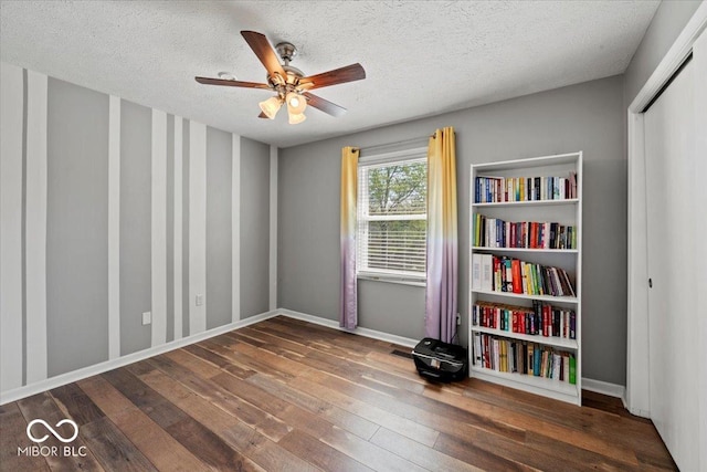 empty room with baseboards, wood-type flooring, a ceiling fan, and a textured ceiling
