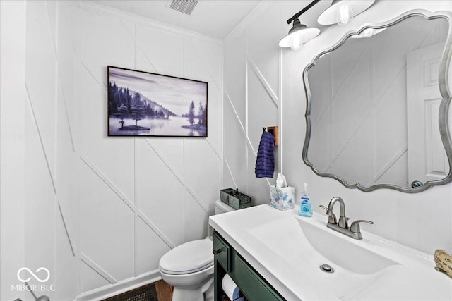 half bathroom with crown molding, toilet, visible vents, and vanity