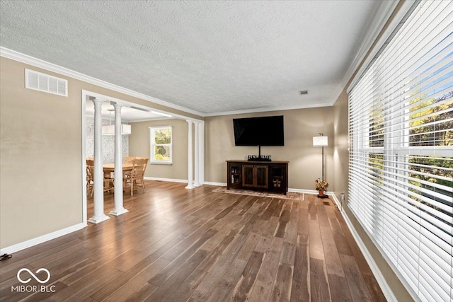 unfurnished living room featuring visible vents, decorative columns, and wood finished floors