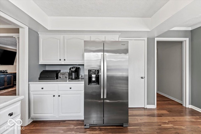 kitchen featuring stainless steel fridge, light countertops, white cabinets, and dark wood finished floors
