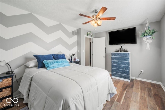 bedroom with a ceiling fan, baseboards, visible vents, and wood finished floors