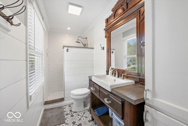 bathroom featuring toilet, ornamental molding, tiled shower, and vanity