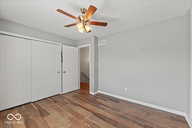 unfurnished bedroom with baseboards, a textured ceiling, hardwood / wood-style floors, and visible vents