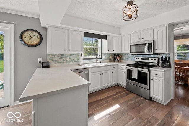 kitchen featuring stainless steel appliances, a textured ceiling, a sink, and a peninsula