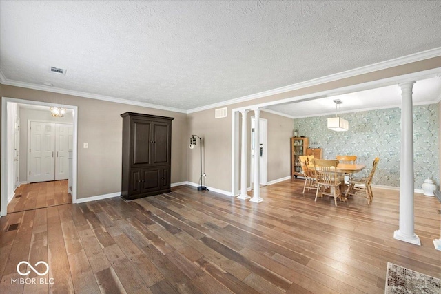 interior space featuring ornate columns, baseboards, and hardwood / wood-style floors