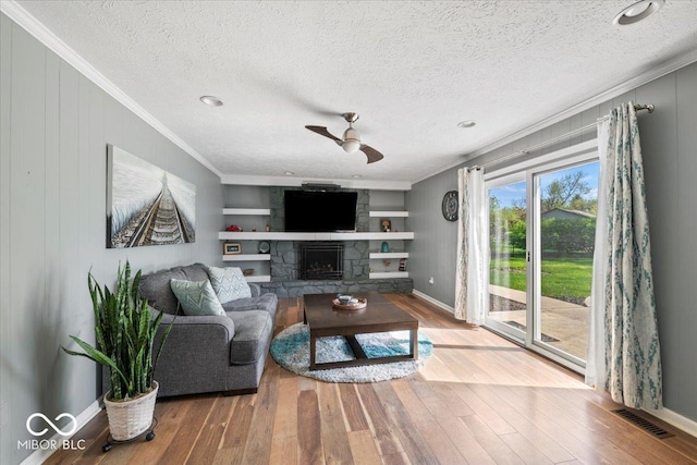 living area with crown molding, ceiling fan, visible vents, and wood finished floors