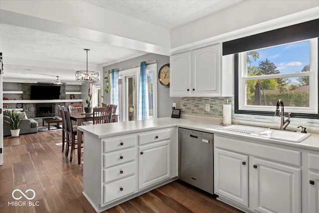 kitchen with a sink, a textured ceiling, white cabinetry, open floor plan, and stainless steel dishwasher