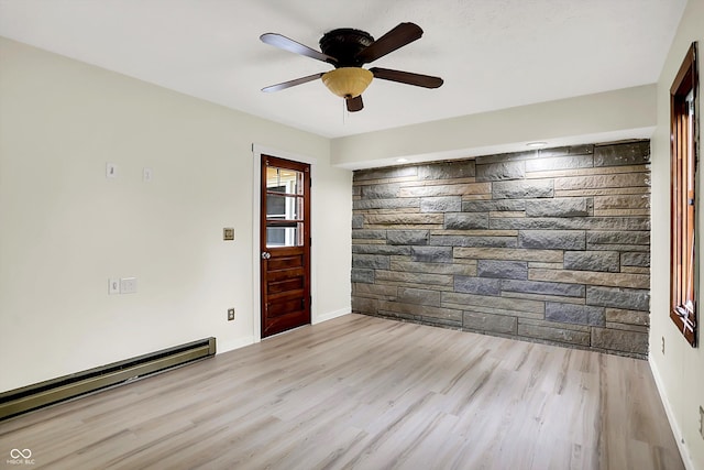 spare room featuring wood finished floors, a ceiling fan, a baseboard heating unit, and baseboards