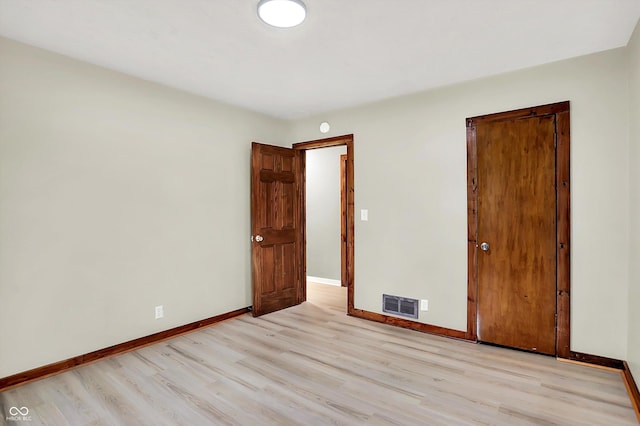 empty room featuring visible vents, light wood-style flooring, and baseboards
