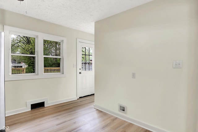 interior space featuring a textured ceiling, light wood-type flooring, and baseboards