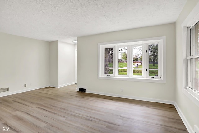 unfurnished living room featuring a textured ceiling, a wealth of natural light, and wood finished floors
