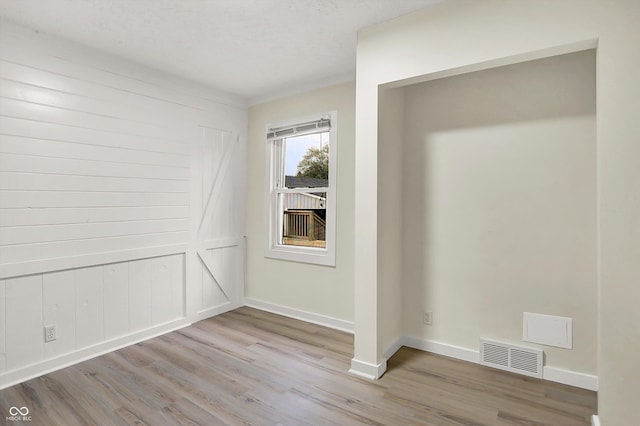 empty room with baseboards, visible vents, and wood finished floors