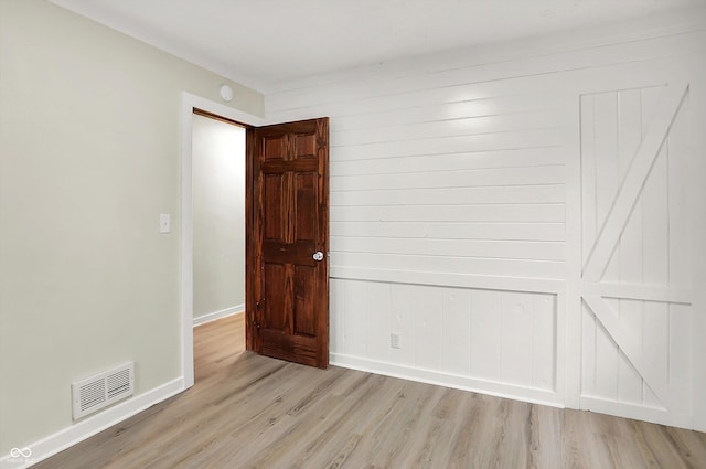 empty room featuring visible vents, light wood-style flooring, and baseboards
