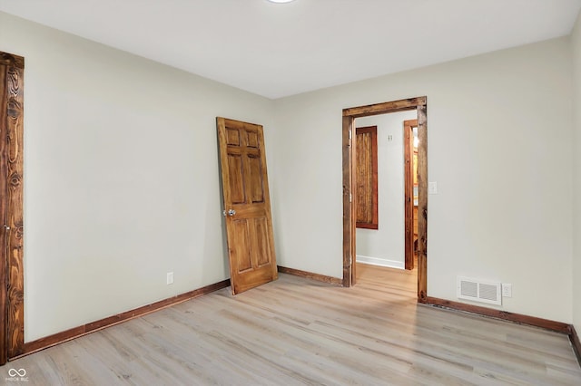 unfurnished room featuring visible vents, light wood-style flooring, and baseboards