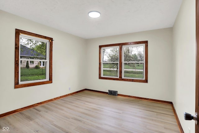 spare room with visible vents, light wood finished floors, and baseboards