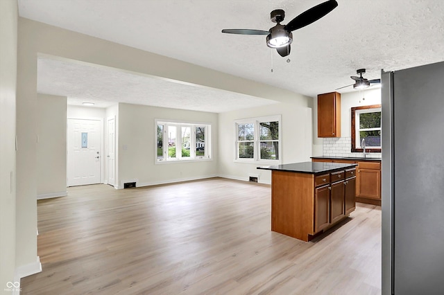 kitchen featuring a textured ceiling, ceiling fan, freestanding refrigerator, and light wood-type flooring