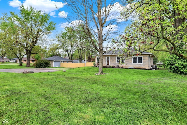 view of yard featuring driveway, a garage, and fence