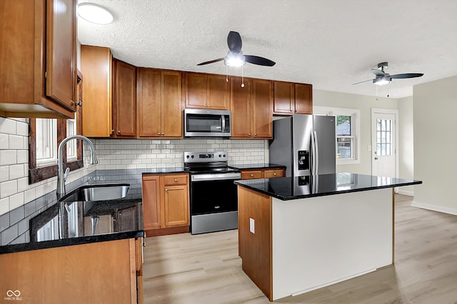 kitchen featuring light wood-style flooring, a ceiling fan, a sink, and appliances with stainless steel finishes