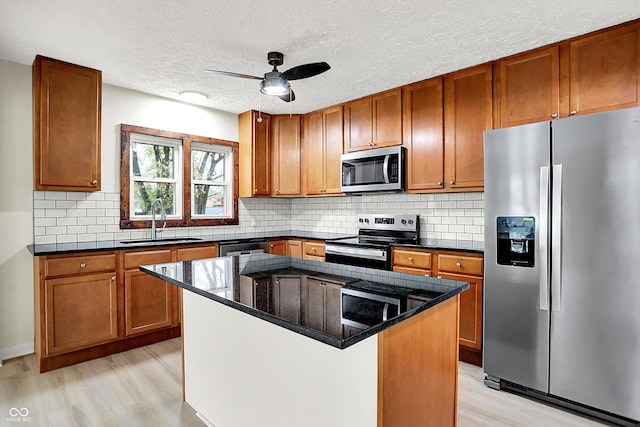 kitchen featuring light wood-style flooring, a ceiling fan, a sink, and appliances with stainless steel finishes