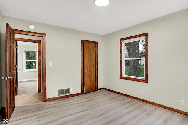 unfurnished room featuring visible vents, light wood finished floors, and baseboards