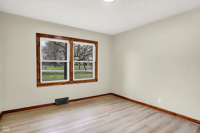 unfurnished room with visible vents, light wood-style flooring, and baseboards