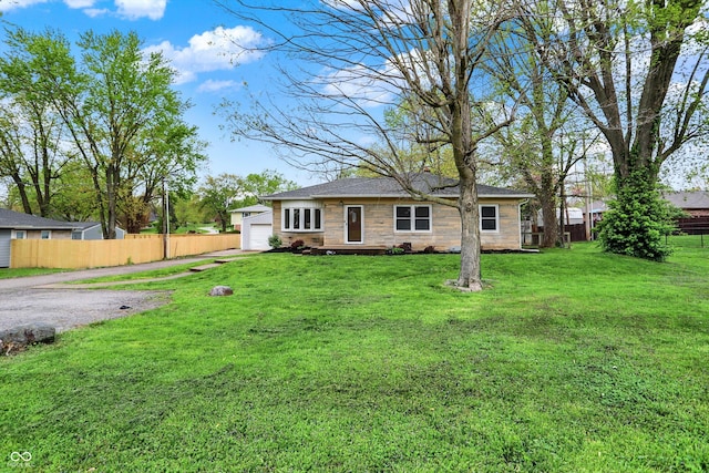 ranch-style house with fence, a garage, driveway, stone siding, and a front lawn