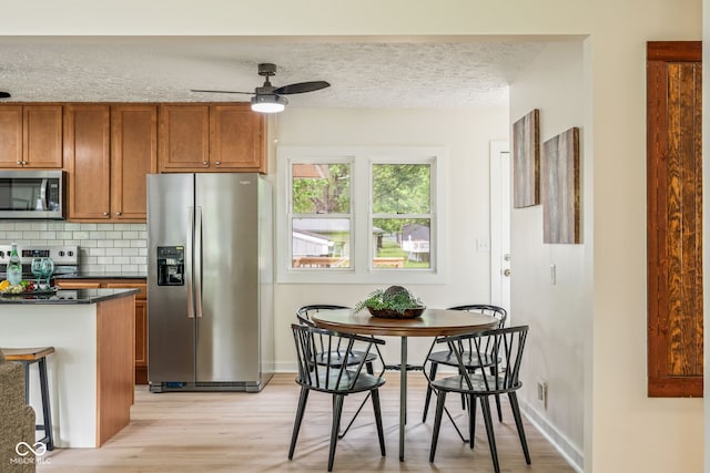 840 N Indiana St, Mooresville, IN 46158 - kitchen featuring stainless steel appliances, brown cabinets, a ceiling fan, light wood-style floors, and dark countertops