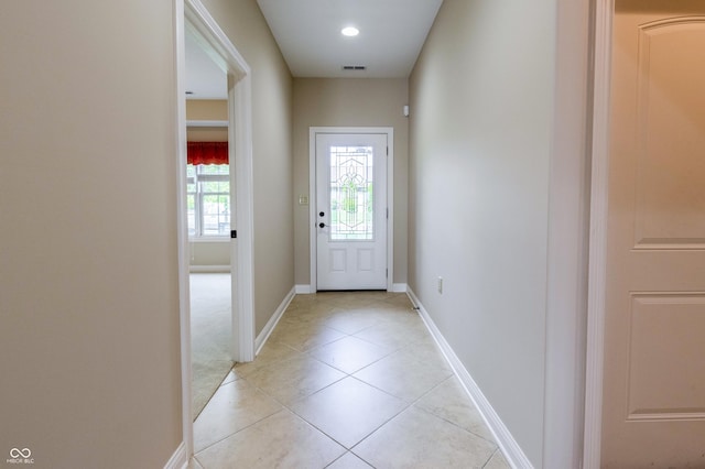 doorway to outside with light tile patterned floors, baseboards, and visible vents