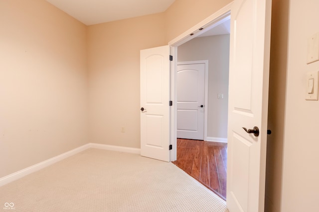 unfurnished room featuring baseboards and light carpet