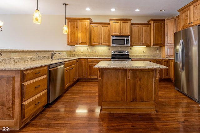 kitchen with stainless steel appliances, light stone countertops, brown cabinetry, and a sink