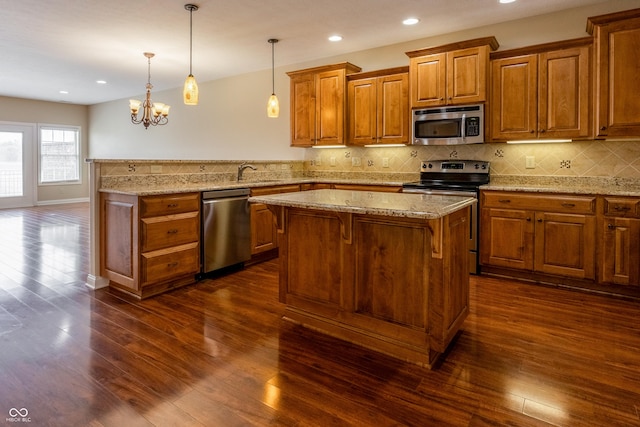 kitchen with dark wood-style flooring, a peninsula, brown cabinets, and stainless steel appliances
