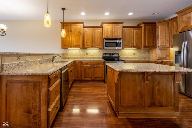 kitchen featuring brown cabinets, stainless steel appliances, light stone counters, and dark wood-type flooring