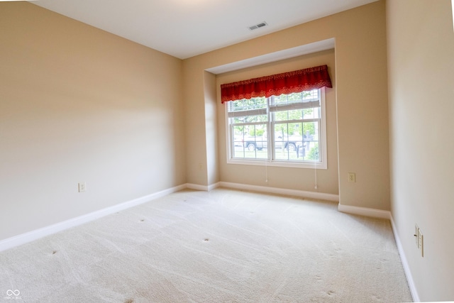 unfurnished room featuring visible vents, baseboards, and light colored carpet