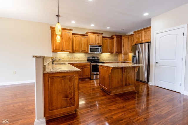 kitchen featuring light stone countertops, appliances with stainless steel finishes, a breakfast bar, a sink, and dark wood-style floors