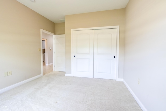 unfurnished bedroom with baseboards, carpet, and a closet