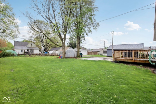 view of yard with an outbuilding, a shed, a deck, and a residential view