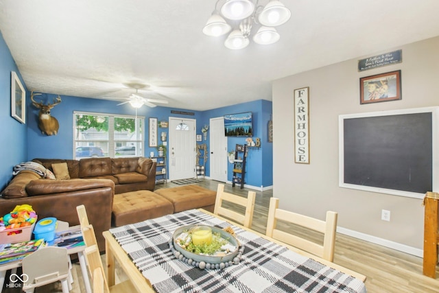 dining space with baseboards, wood finished floors, and ceiling fan with notable chandelier