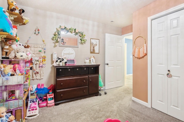 playroom featuring a textured ceiling and carpet flooring