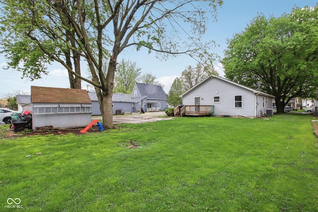 view of yard with a deck, a shed, an outbuilding, and central AC