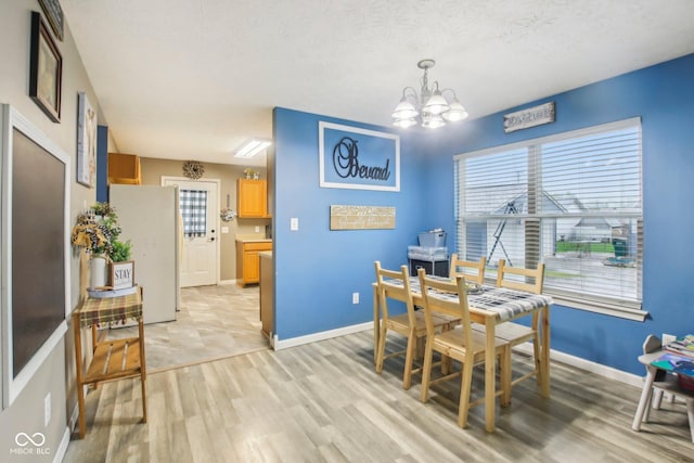 dining space featuring light wood finished floors, an inviting chandelier, and baseboards