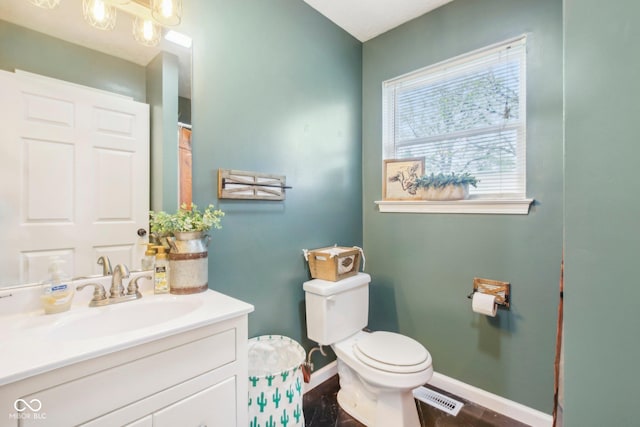 bathroom with wood finished floors, toilet, vanity, baseboards, and visible vents