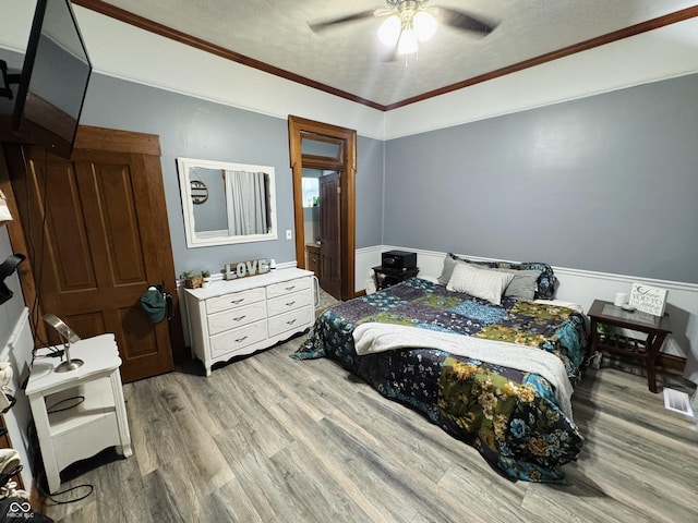 bedroom with a textured ceiling, wood finished floors, and ornamental molding