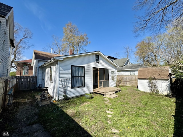 rear view of house featuring a chimney, an outdoor structure, a fenced backyard, a shed, and a lawn