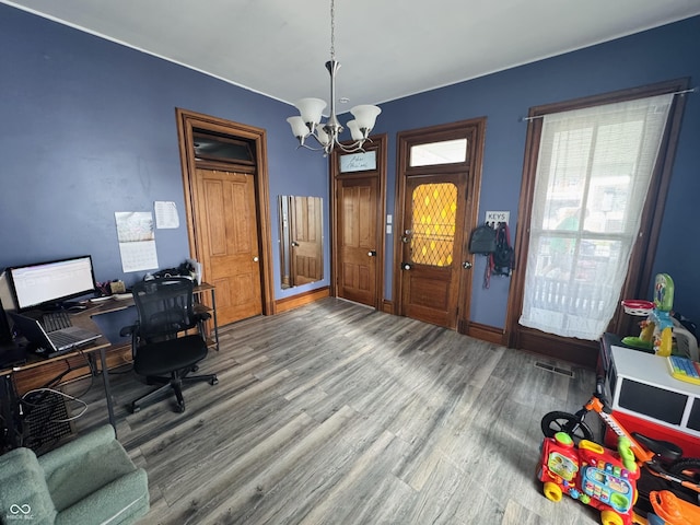 home office with a chandelier, visible vents, and wood finished floors