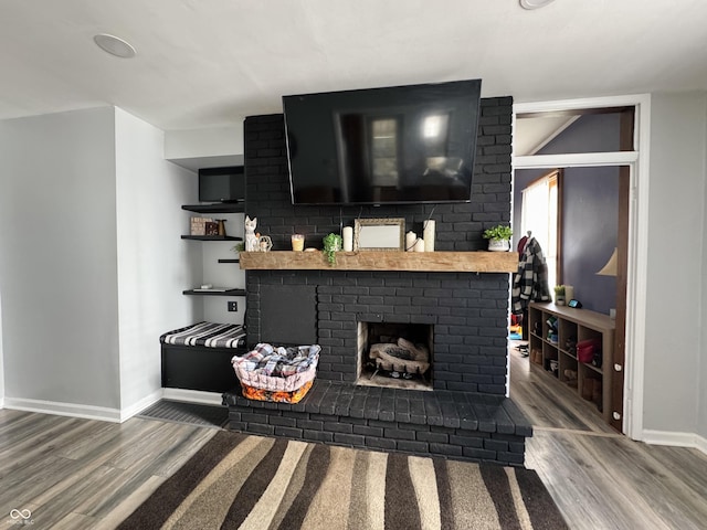 living room with a brick fireplace, wood finished floors, and baseboards