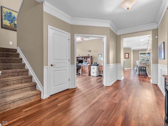 entrance foyer featuring stairway, wood finished floors, a wainscoted wall, and crown molding