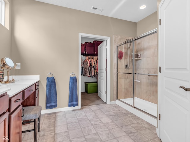 full bath with baseboards, a shower stall, vanity, a walk in closet, and visible vents